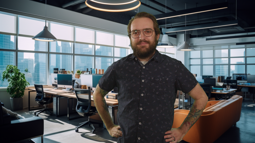 Michael, bearded with glasses and tattoos visible on his arms, stands with his hands on his hips in a modern office environment. He wears a short-sleeved button-up shirt with a subtle pattern. The spacious office behind him features large windows with views of skyscrapers, numerous desks with computer setups, and a casual lounge area with a plush orange couch. The ambiance is professional and stylish, with a mix of natural and artificial light creating a welcoming workspace.